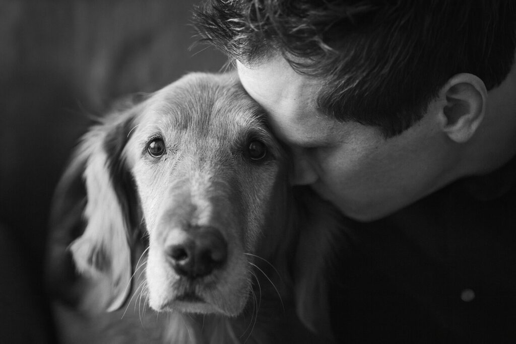 Proprietario che abbraccia il cane in un momento intimo in bianco e nero, sguardo del cane emozionato rivolto verso la camera